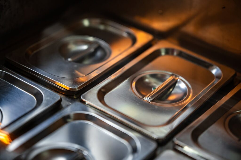 Stacks of shiny stainless steel food containers in a professional kitchen setting.